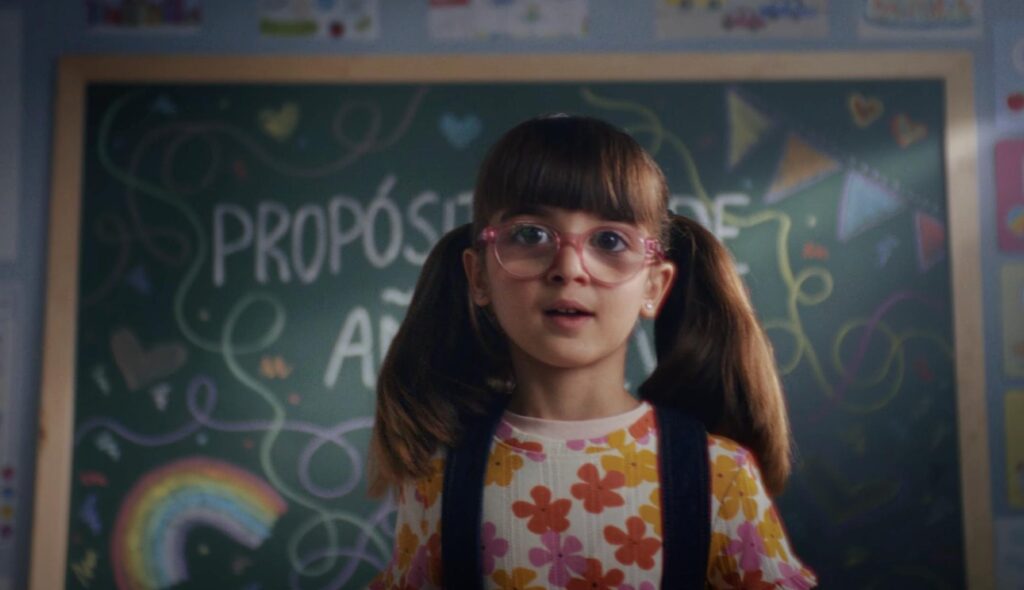 Niña con gafas delante de un pizarra