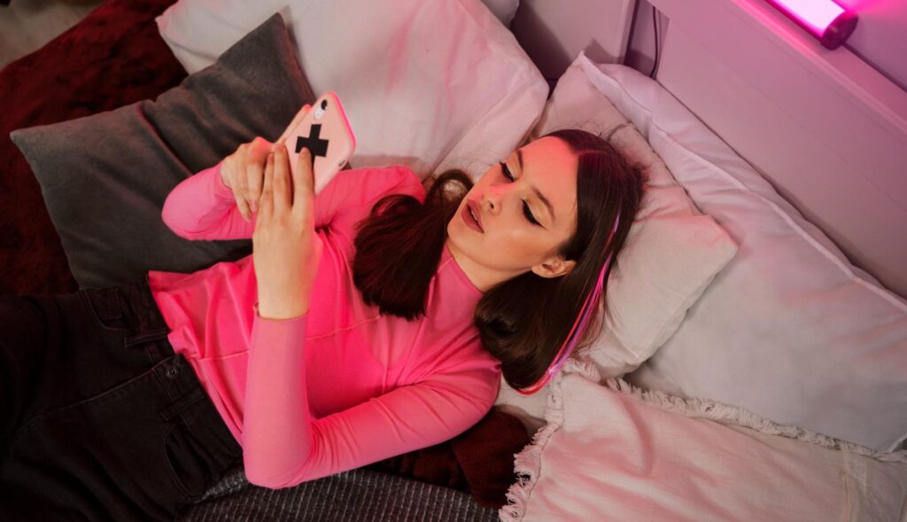 chica joven con teléfono móvil tumbada en una cama
