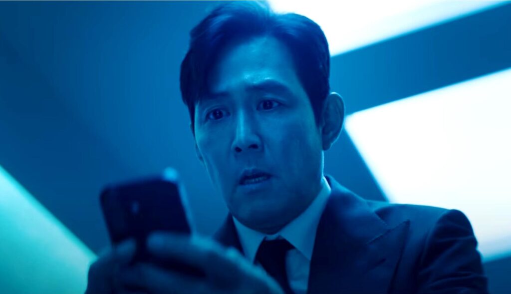 El actor Lee Jung-jae de "El juego del calamar" sujetando un móvil con cara de preocupación