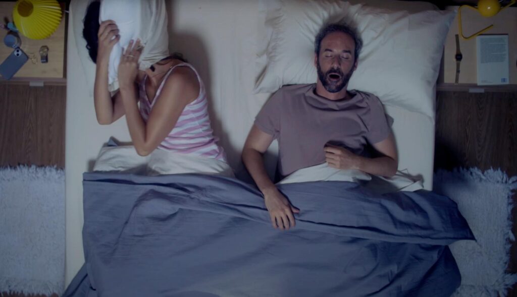 Una pareja durmiendo en la cama. Ella intentándolo y él roncando