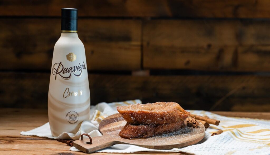 nueva torrija de Levaduramadre con crema Ruavieja, sobre una tabla y junto a una botella de la bebida