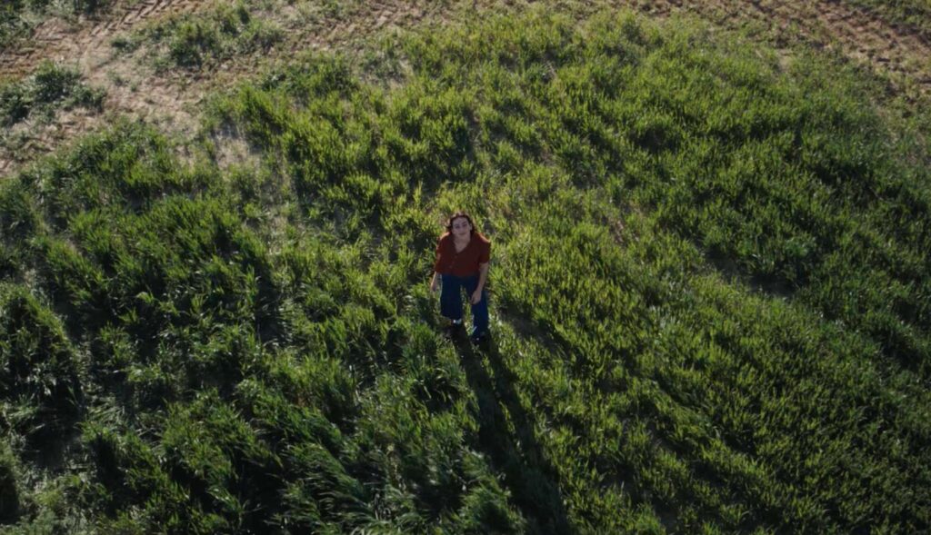 Mujer joven mira al cielo desde un campo verde