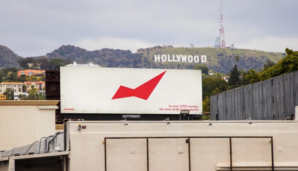 valla publicitaria de Budweiser en lo alto de un edificio, con la señal de Hollywood en Los Ángeles de fondo