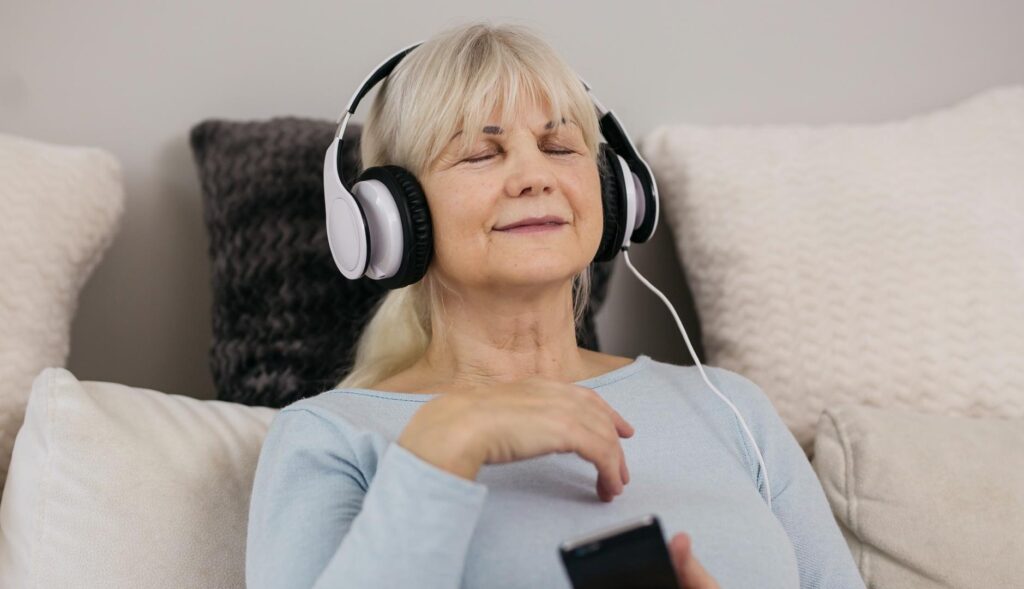 una mujer escuchando musica con el movil y los ojos cerrados, disfrutando del momento
