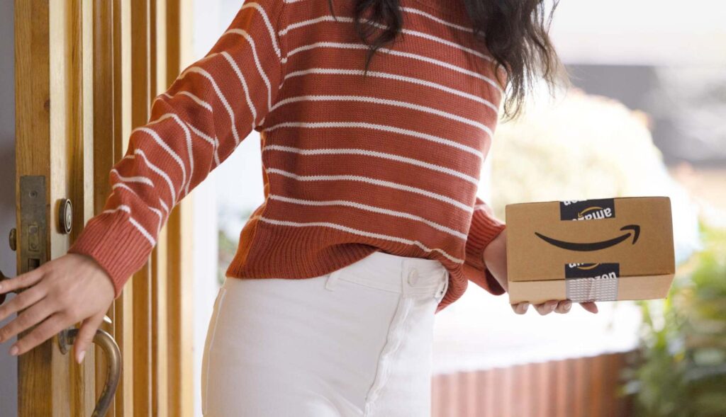 Chica con un paquete de Amazon en la mano