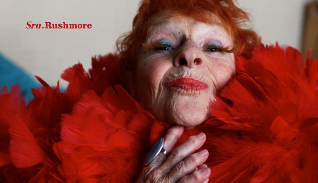 Una mujer mayor pelirroja con plumas rojas