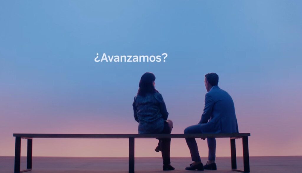 Imagen de dos personas sentadas en un banco con fondo azul