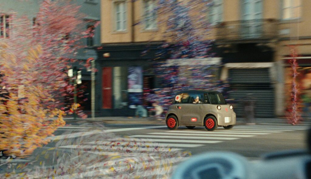 Un Citroën Ami por la ciudad circulando entre confeti