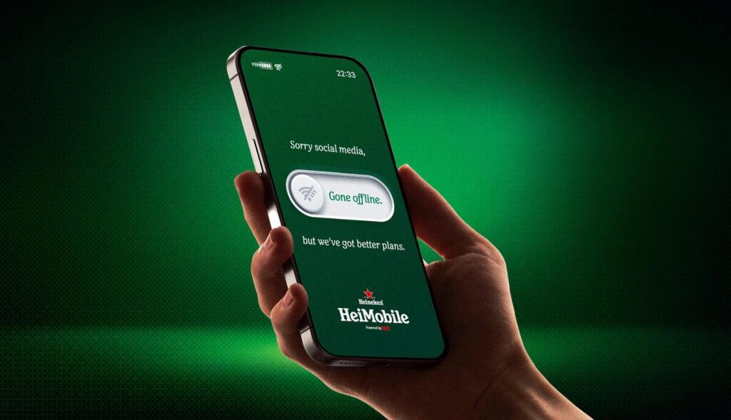 Mano sujetando un teléfono móvil con un mensaje de Heineken
