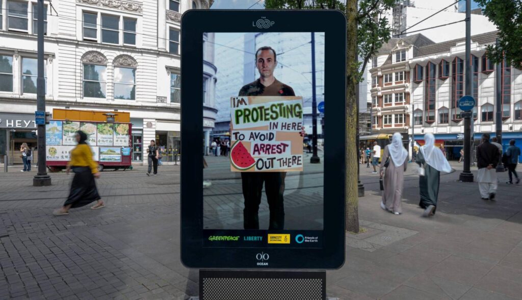 Persona sujetando una pancarta en un mupi digital