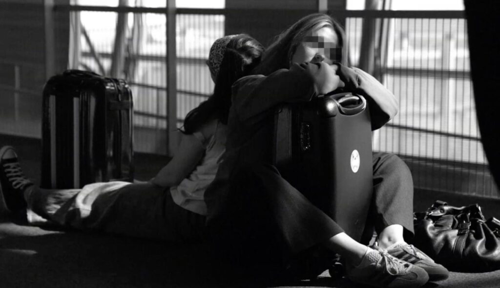 dos chicas durmiendo en el suelo del aeropuerto con las maletas