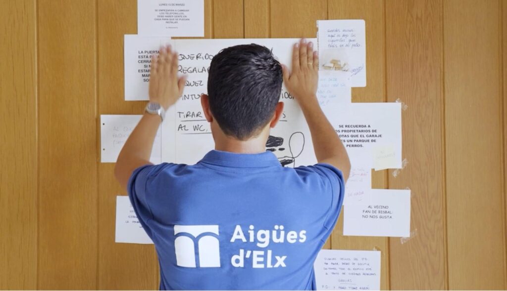 un hombre colgando un cartel en el tablón de anuncios del portal