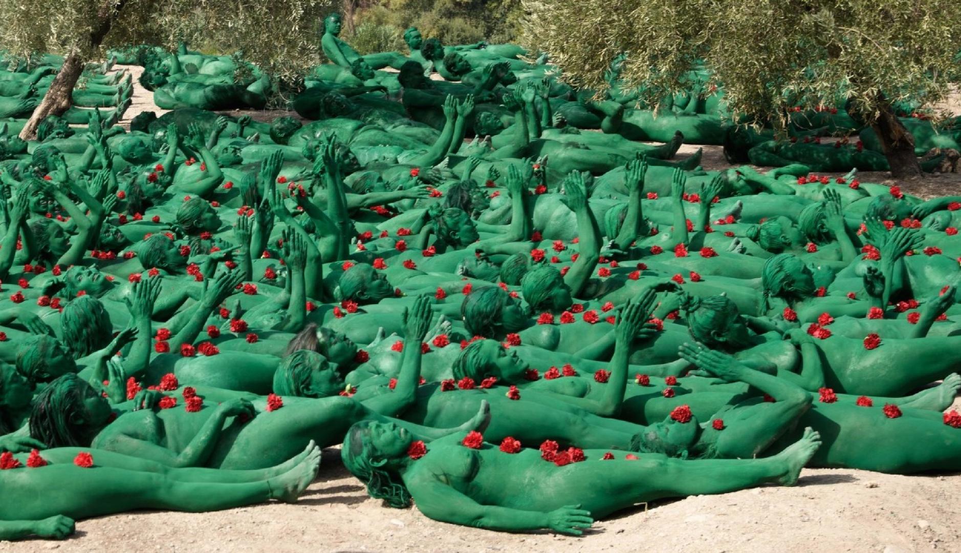 personas con el cuerpo pintado de verde tumbadas en el suelo en el campo