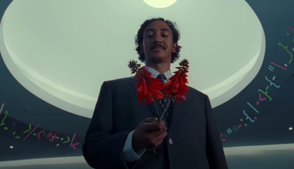 Un hombre de traje sujeta unas flores rojas