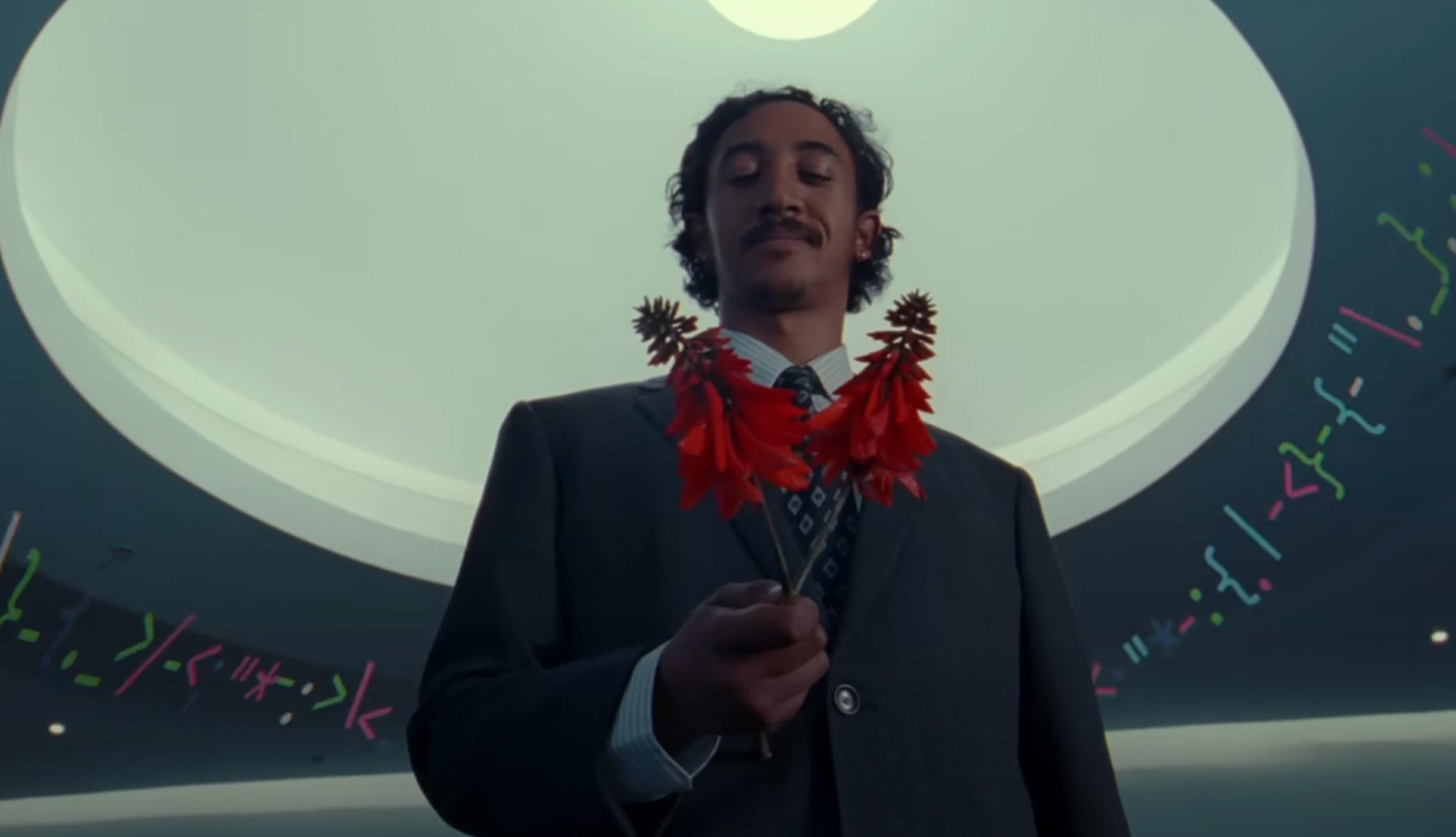 Un hombre de traje sujeta unas flores rojas