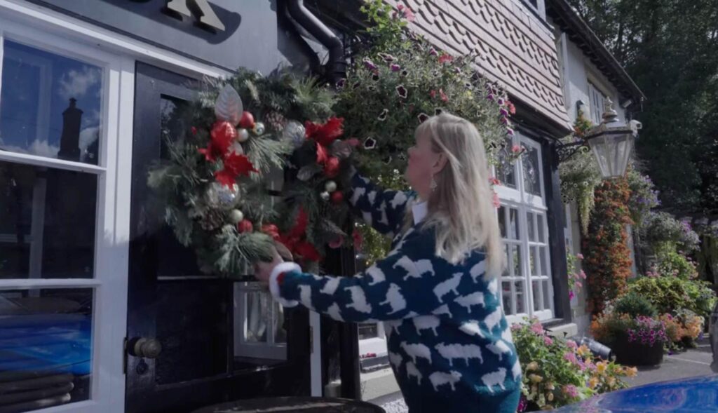 Mujer decorando su casa con una corona de Navidad