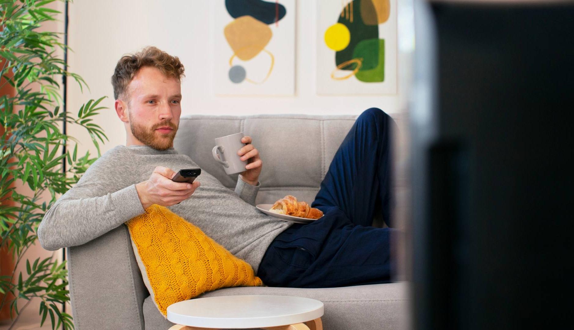 Hombre viendo la televisión tumbado en el sofá