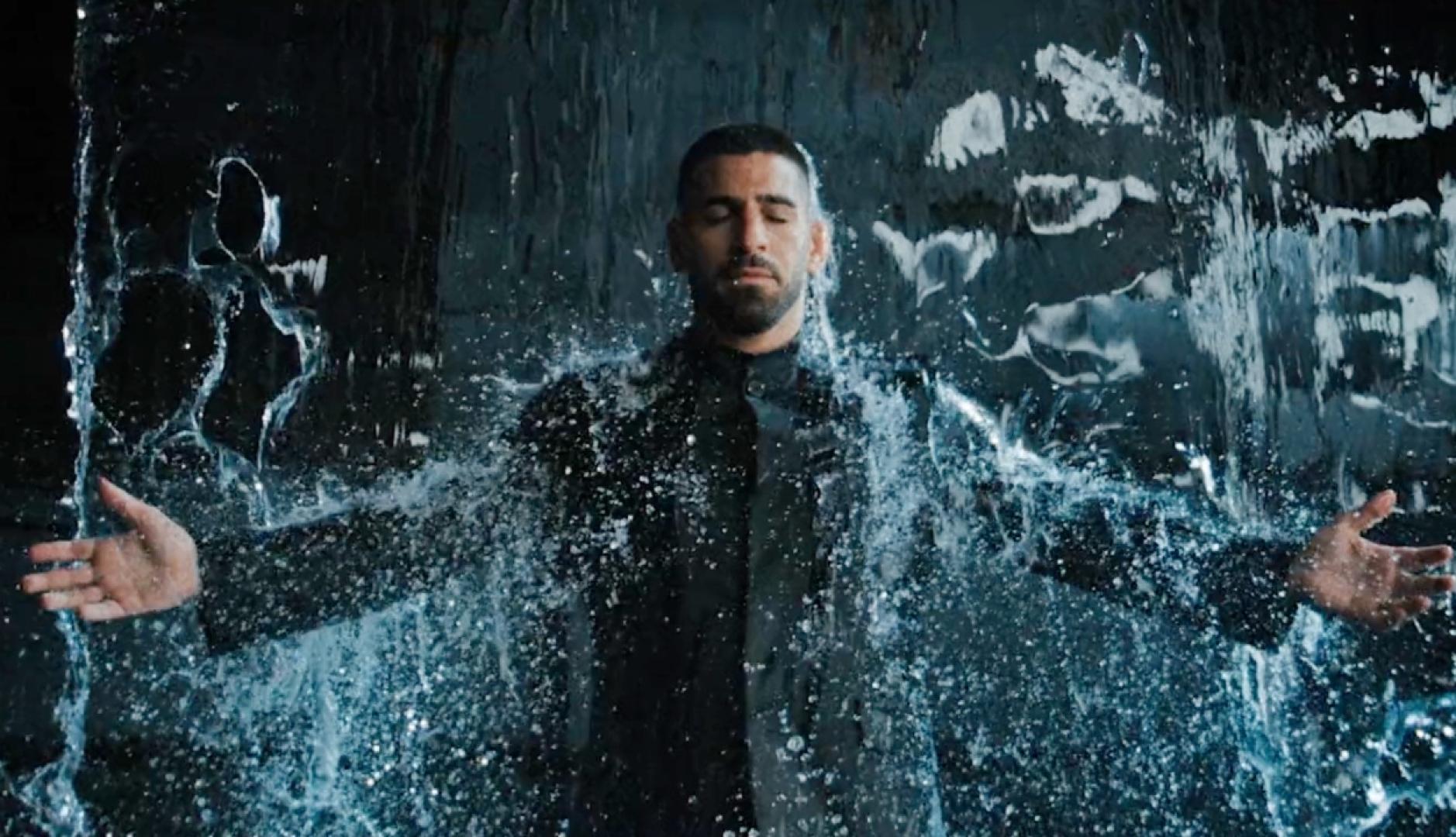 Ilia Topuria con los brazos en cruz bajo una cortina de agua vestido