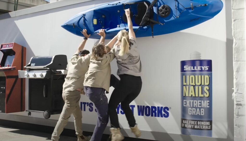 Tres personas intentando despegar un kayak de una pared