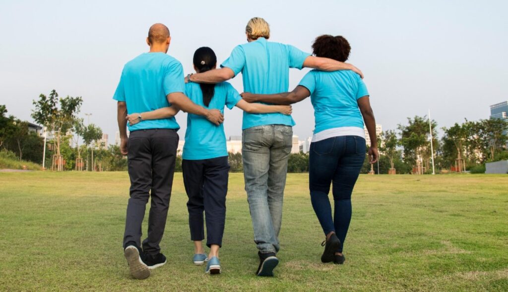 Un equipo de espaldas se abraza, vestidos todos con polos azules
