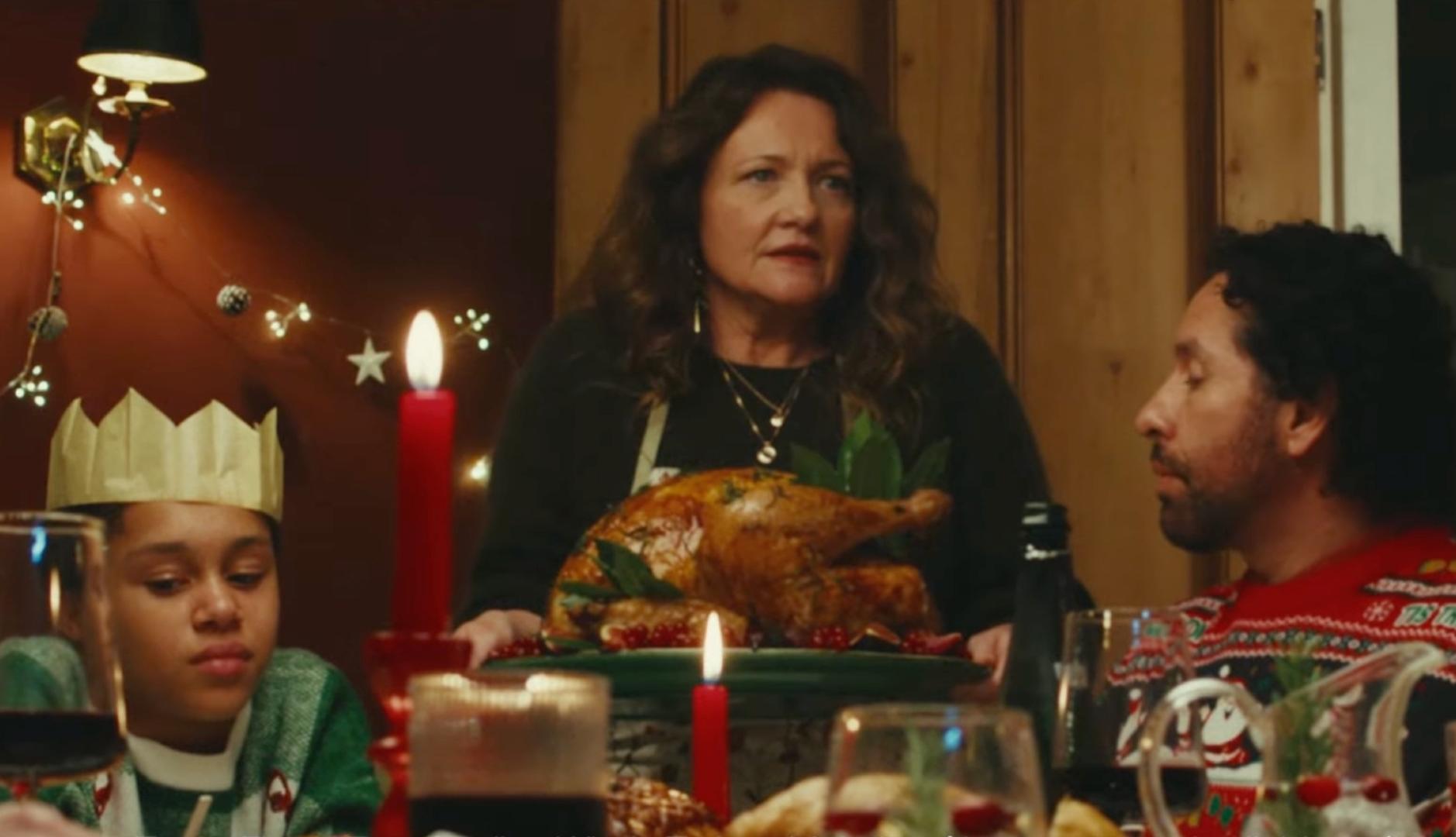 Una mujer sostiene un pavo en una cena de Navidad familiar