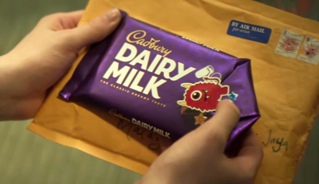 Unas manos que sostienen la tableta de Cadbury usada y cerrada con una pegatina