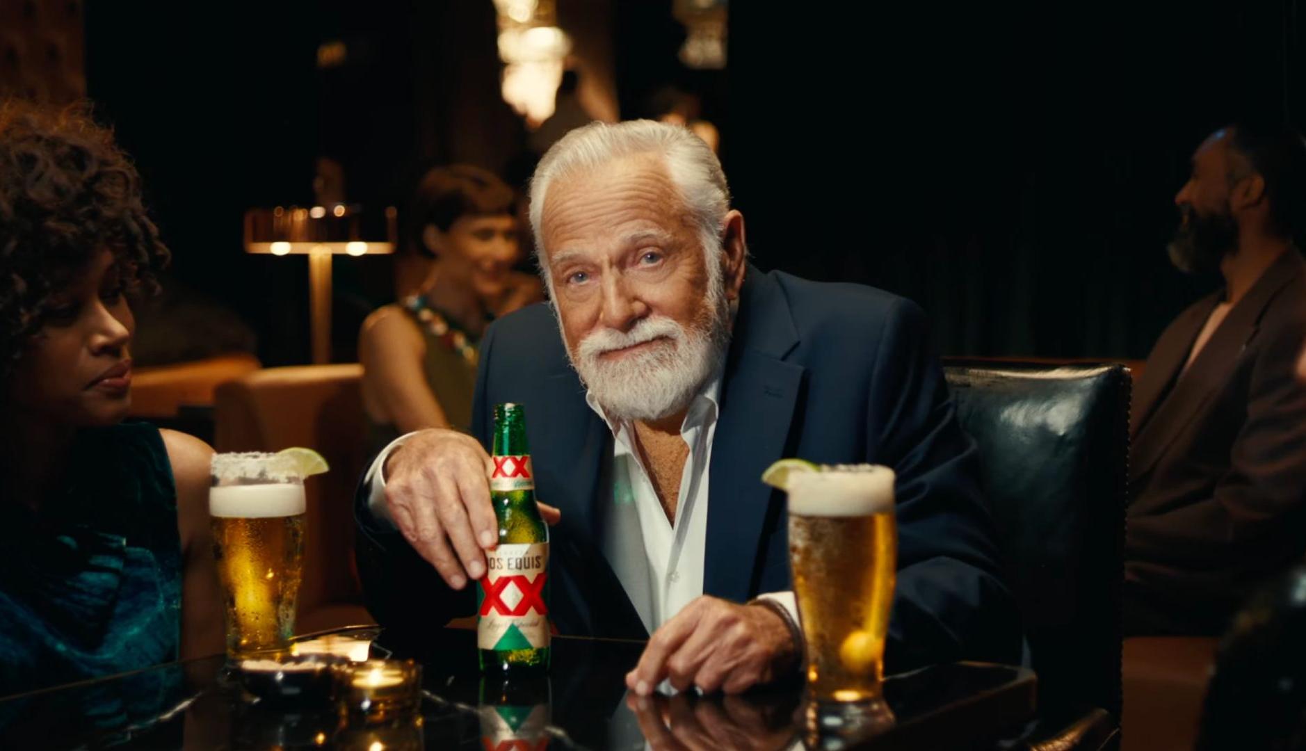 Hombre con barba blanca bebe cerveza Dos Equis en un bar