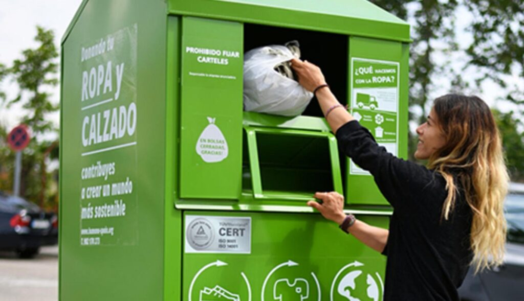 Una mujer depositando una bolsa de ropa en un contenedor de Humana