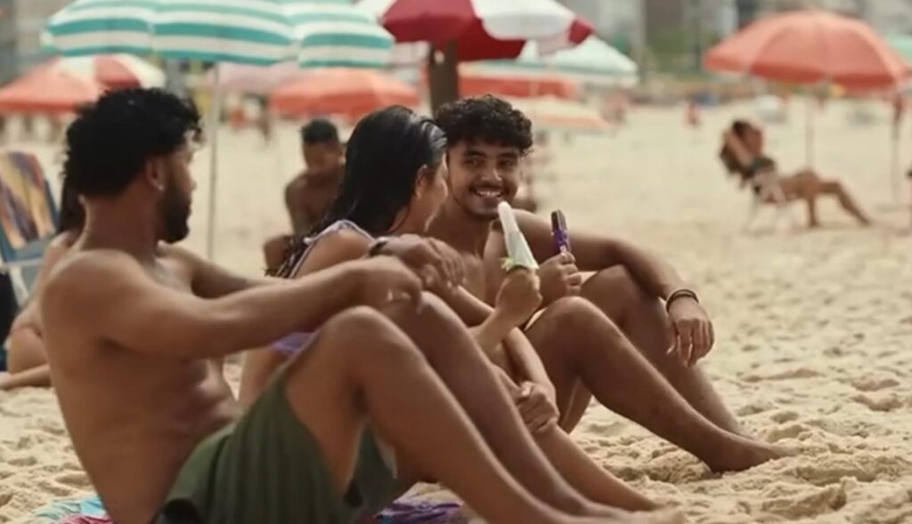 Tres personas jóvenes comen helado en una playa