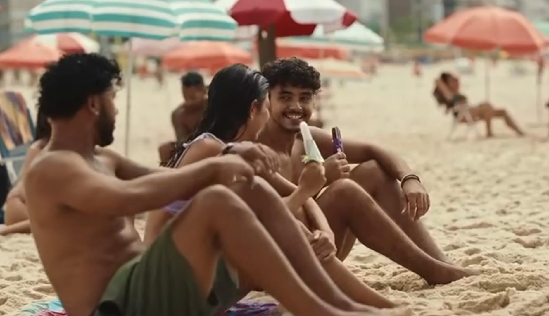 Tres personas jóvenes comen helado en una playa