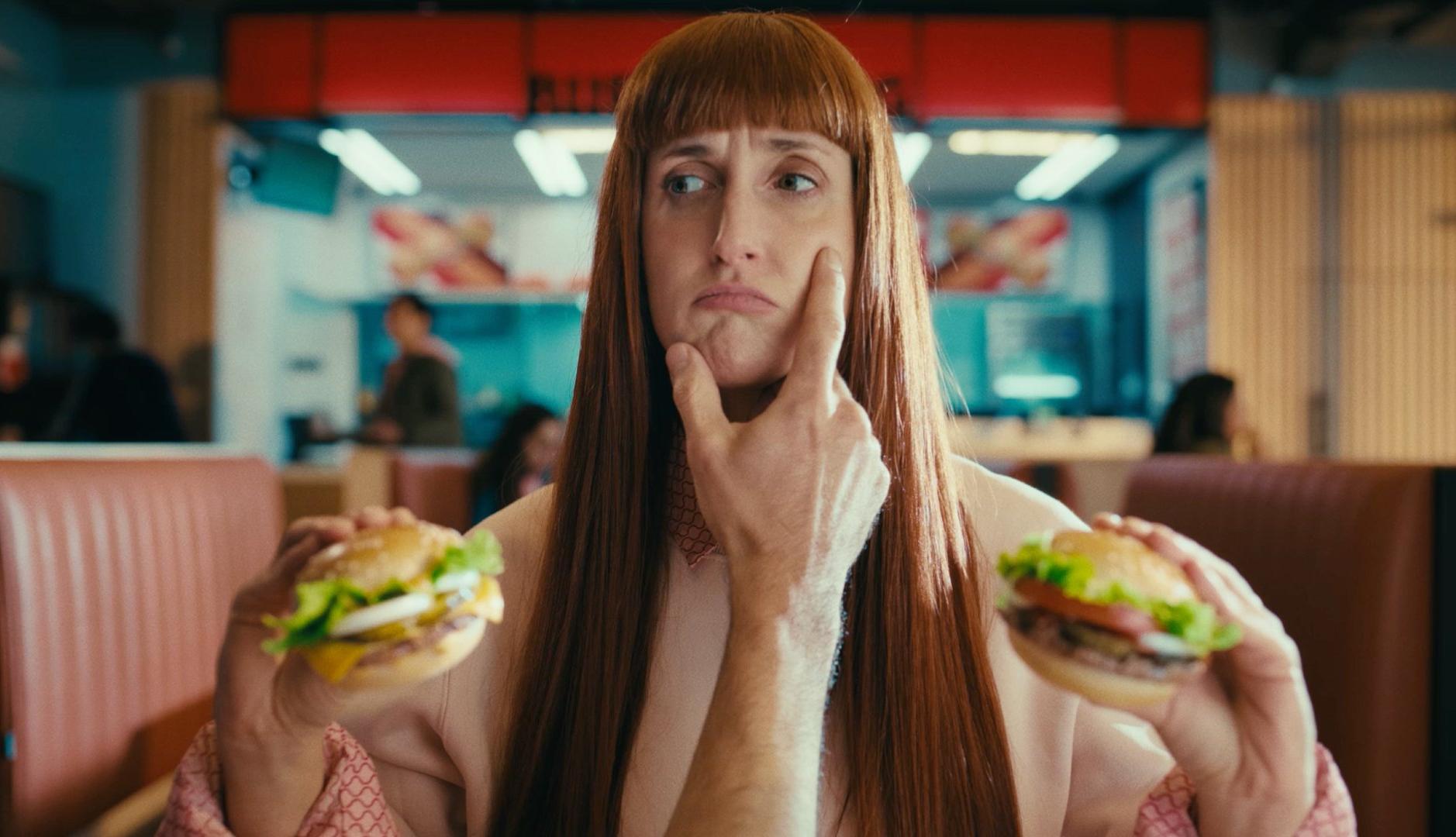 Una mujer sostiene una hamburguesa mini en cada mano