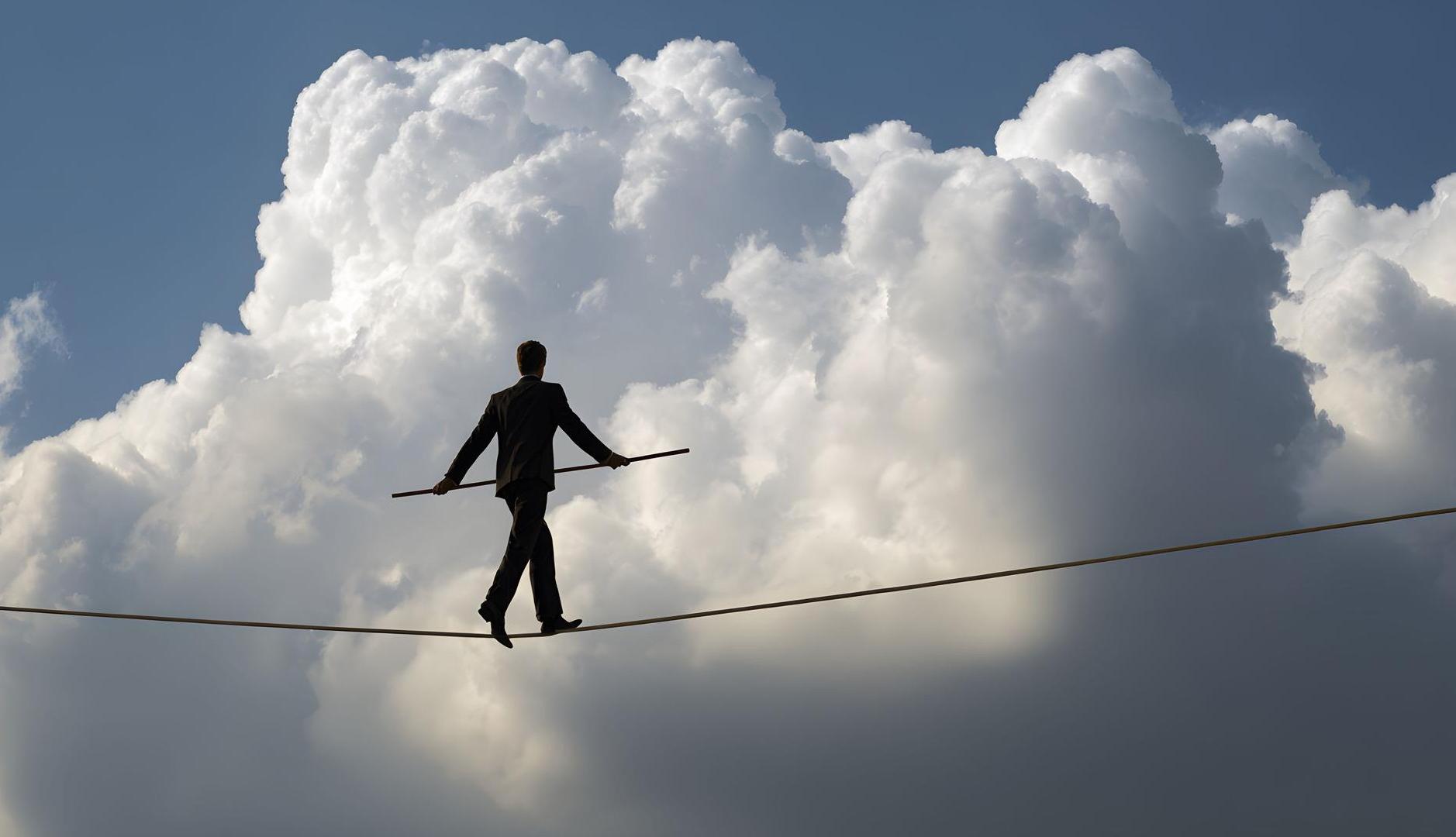 Hombre haciendo equilibrios sobre una cuerda con nubes de fondo