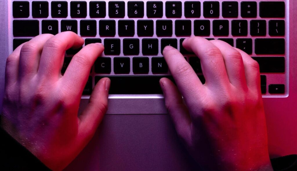 Una manos sobre el teclado de un ordenador portátil