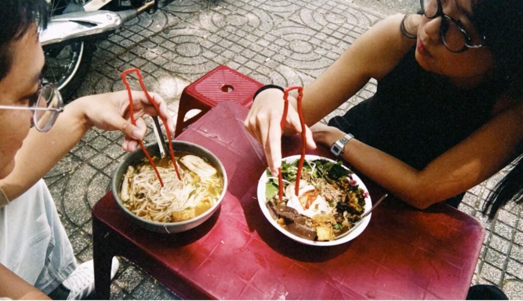 Una pareja comiendo ramen con los palillos rojos de coca-cola