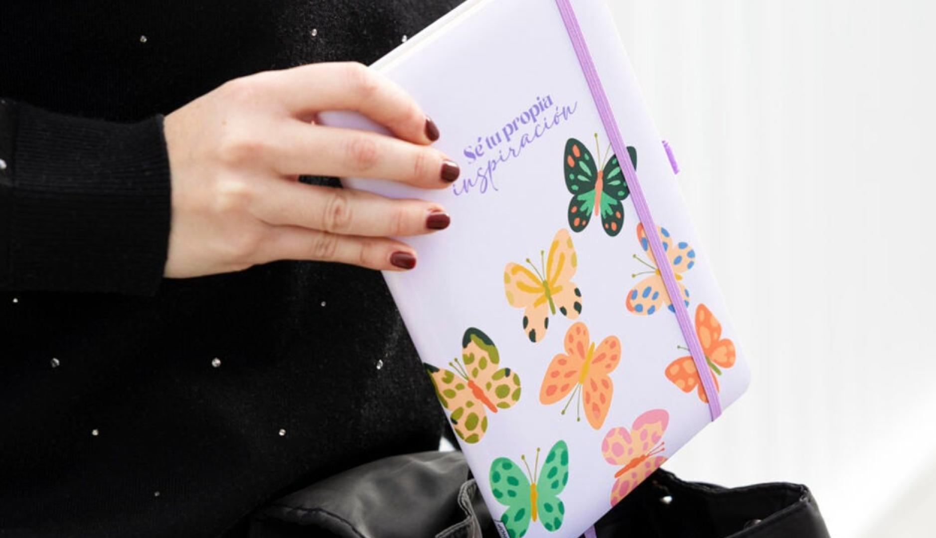 Una mano de mujer sosteniendo una libreta en la que se lee la frase