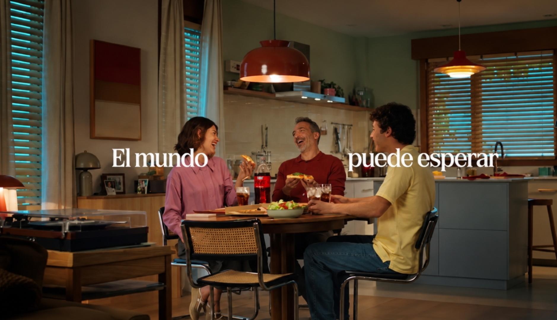 Un padre y sus dos hijos sentados a la mesa comiendo pizza y riendo